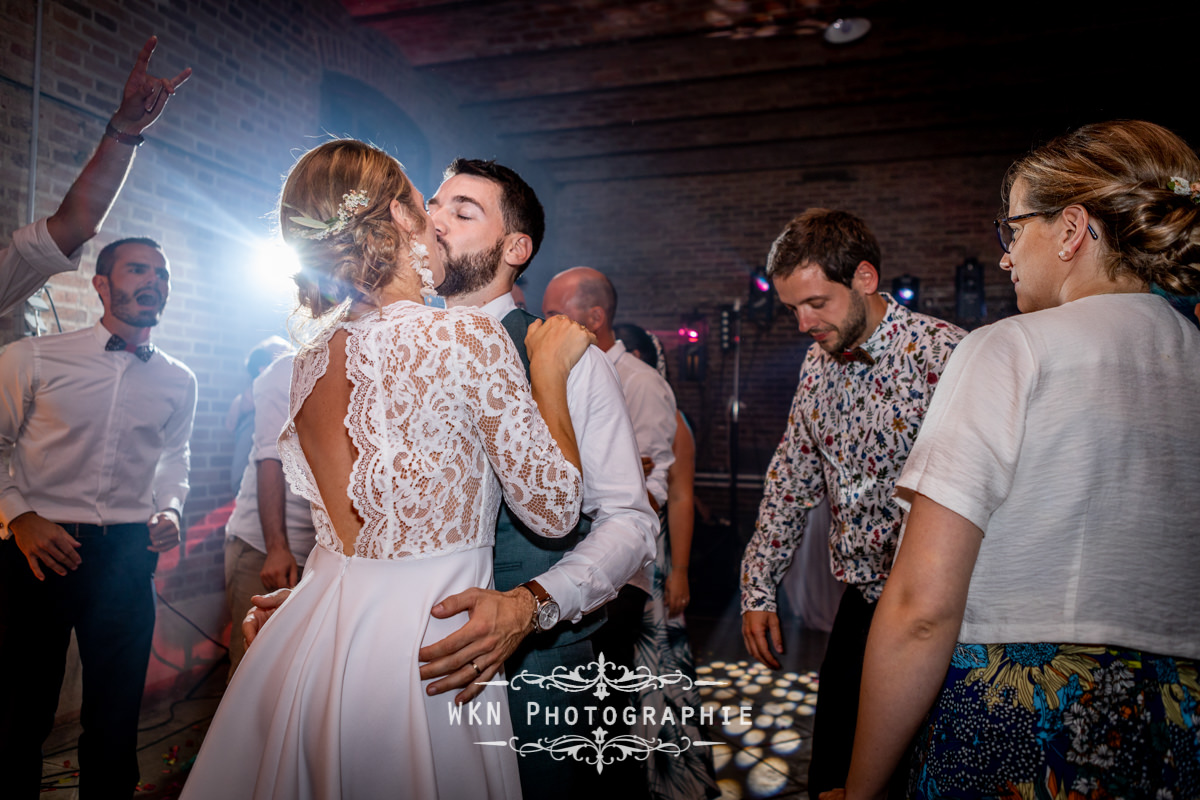 Claire et Corentin échangent un tendre baiser pendant leur première danse, entourés de l'amour et des sourires de leurs proches.
